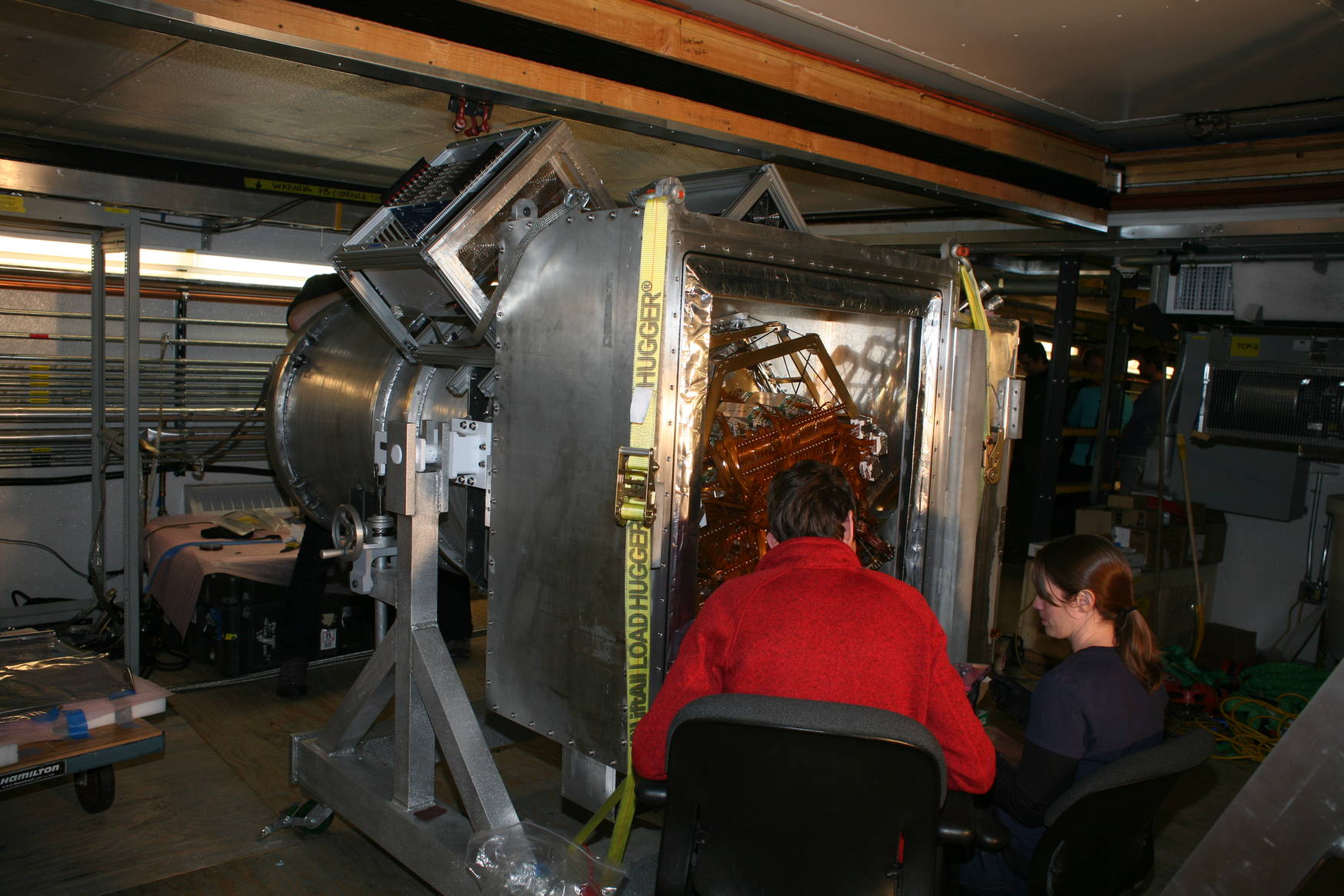 I am somewhat lucky to arrive on this particular day. Parts of the detector are still open and it's very nice to see what it looks like on the inside. This picture shows the new receiver ('camera') to be mounted on the telescope. The cylindrical part facing away contains the optics, and the square box that houses the detector and read-out electronics is still open. Two of my colleagues are working on finishing the assembly before closing the back. 