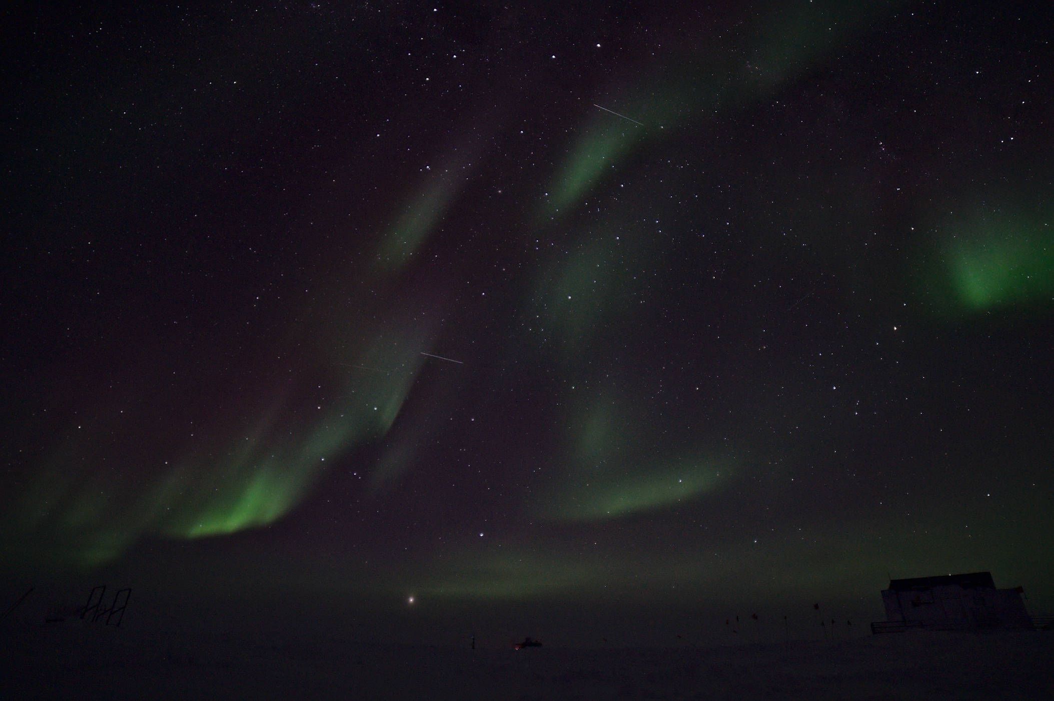 This pictures was taken just a few hours after the previous one. It illustrates nicely how much auroras change, we can literally watch them change from minute to minute. It is really quite marvelous. In the bottom right corner is building 61, the power and communication's distribution hub of the dark sector. The tracks of two satellites can be seen, the upper one is probably a flare from an Iridium satellite that we use for communications. The constellation of Scorpio is visible to the right and the Southern cross with the two pointer stars in Centaurus are visible at the very top of the image.